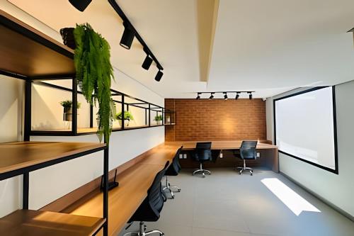 ein Büro mit einem langen Tisch und Stühlen in der Unterkunft Loft 306 - Praticidade e estilo na esquina da Ufu in Uberlândia
