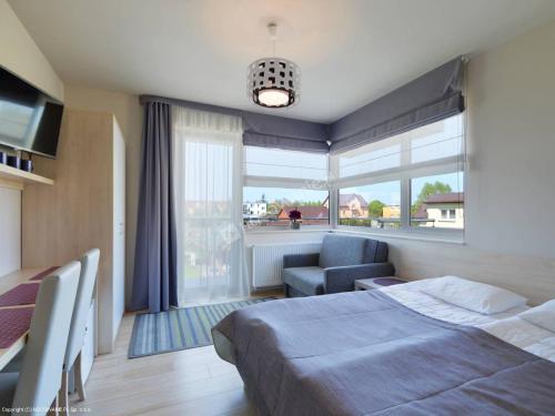 a bedroom with a bed and a chair and a window at Villa Martika in Ustronie Morskie