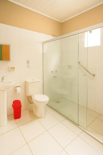 a bathroom with a toilet and a glass shower at Complejo de Apartamentos parque naturaleza in Encarnación