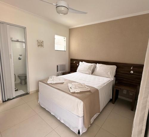 Un dormitorio con una gran cama blanca y un baño. en Pousada Mariá, en Cabo Frío