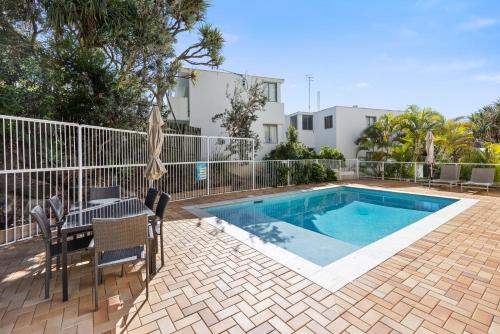 a swimming pool with a table and chairs next to a house at Aqua Promenade Beachfront Holiday Apartments in Sunrise Beach