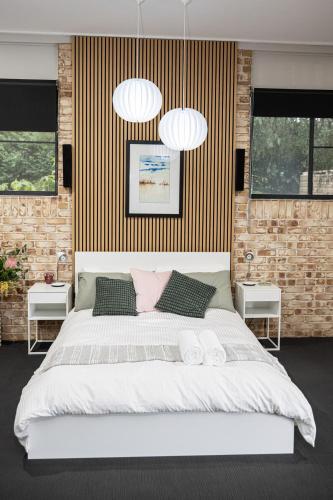 a bedroom with a large white bed with two lamps at Mirambeena Retreat in Toowoomba