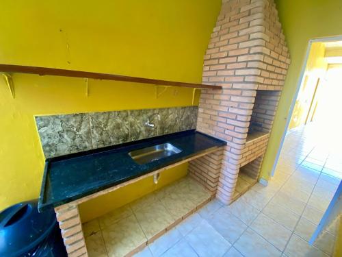 a kitchen with a sink and a brick fireplace at Casa Gonzalez Oliveira in Mongaguá