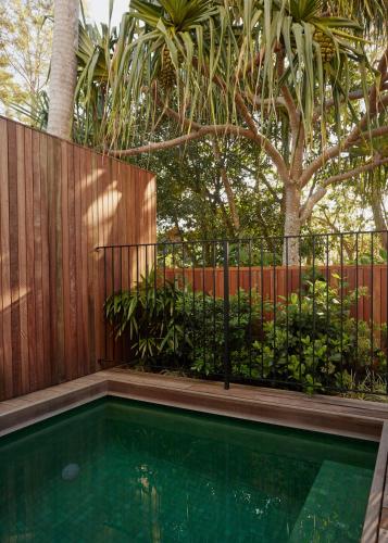 a swimming pool in front of a wooden fence at 28 Degrees Byron Bay - Adults Only in Byron Bay