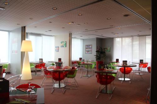 a restaurant with red chairs and tables and windows at ibis Styles Saint Dizier in Saint-Dizier