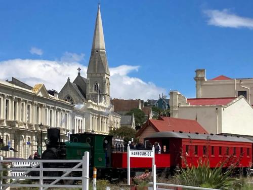 een trein die door een stad met een kerk rijdt bij Seascape on Maude in Oamaru