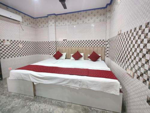 a bedroom with a large white bed with red pillows at Kashi Inn RESIDENCY in Varanasi