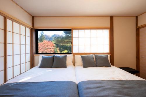 two beds in a room with a window at Nagi GIVE 日光 in Nikko
