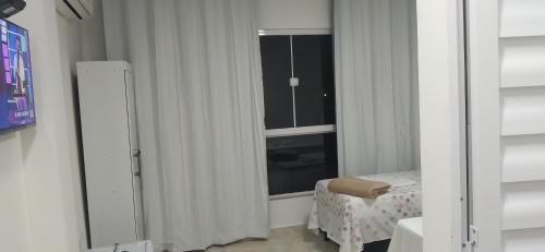 a room with a window and a bed and a mirror at Costa Suítes in Maragogi