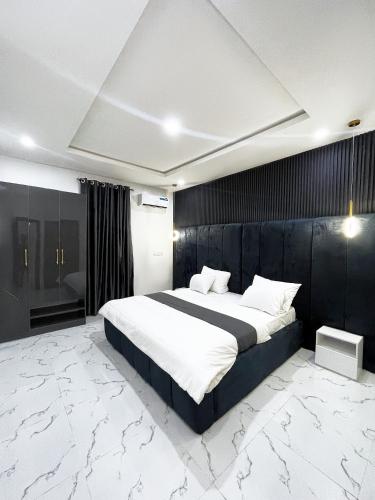 ein Schlafzimmer mit einem großen Bett und einer schwarzen Wand in der Unterkunft Luxurious 2bedroom Apartment PS5 in Ibadan