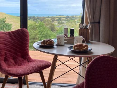 Ein Tisch mit zwei Tellern Croissants darauf vor einem Fenster in der Unterkunft Seascape on Maude in Oamaru