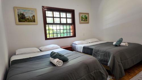 a room with two beds with towels on them at Casa de Campo & Home Office - Itapecerica da Serra , perto do Embu das Artes in Itapecerica da Serra