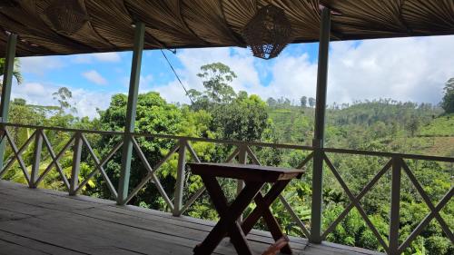 a table on a porch with a view of the forest at Zen Garden Palace in Ella