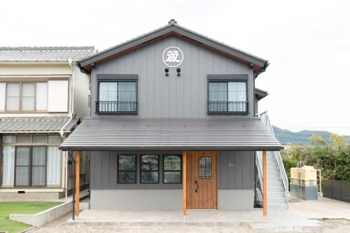 a white house with a brown door at 蔵の宿 in Kamogawa