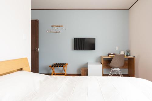 une chambre avec un lit, un bureau et une télévision dans l'établissement 蔵の宿, à Kamogawa