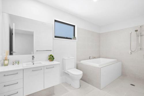 a white bathroom with a toilet and a sink at Seabreeze in Kingscliff