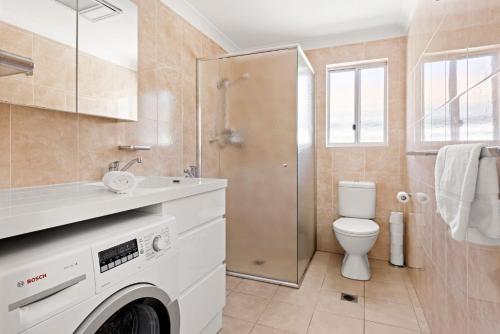 a bathroom with a toilet and a sink and a shower at Villa Burra - Pet Friendly - 5 Mins Walk to the Beach in Culburra Beach