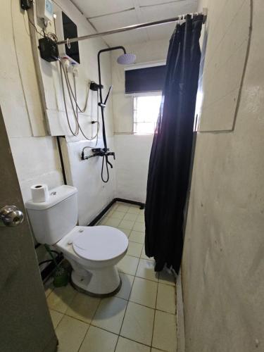 Un baño con inodoro y cortina de ducha. en Furnished 3 Bedroom House near Camp John Hay, en Baguio