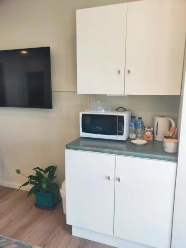 a kitchen with white cabinets and a microwave on a counter at Lakaz Beach house in Omokoroa