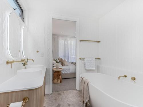 a white bathroom with a tub and a sink at Kai Residences in Cabarita Beach
