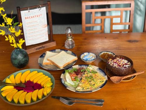 Una mesa de madera con platos de comida encima. en InnerZen Riverside homestay Ben Tre 1 bedroom for 1-2 guests, 2 bedrooms for 3-4 guests, en Ấp Phú Hòa (3)