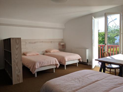 ein Schlafzimmer mit zwei Betten und einem Tisch und einem Fenster in der Unterkunft Maison 3* à Hendaye, proche plage et commerces, jardin privé, parfait pour familles et amis - FR-1-239-492 in Hendaye