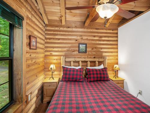 une chambre aux murs en bois et un lit aux draps à carreaux rouges dans l'établissement Good Life Cabin 2, à Bryson City