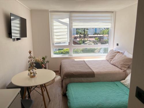 a bedroom with two beds and a table and a window at Central space in Concepción