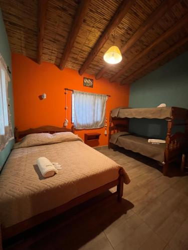 ein Schlafzimmer mit 2 Betten und einer orangefarbenen Wand in der Unterkunft Paraje la bendición in Tilcara