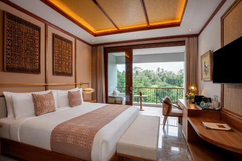 a bedroom with a bed and a desk and a window at Adiwana Alas Harum in Ubud