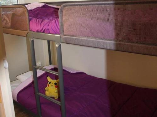 un chien en peluche assis sur la couchette inférieure d'un lit superposé dans l'établissement Chalet 3 étoiles - Piscine - eeedeh, à Guérande
