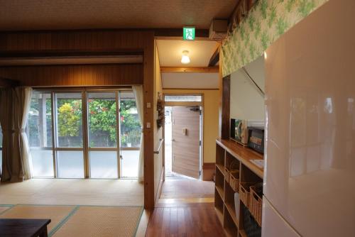 a hallway of a house with a door and a kitchen at 羽地古民家 かめたろうやー in Nakaoshi