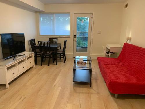 a living room with a red couch and a table at Modern 2-Bedroom suite in Burnaby