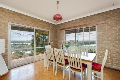 Un comedor con mesa y sillas y ventanas. en River Murray Views, en Nildottie