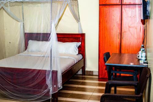 Un dormitorio con una cama, una mesa y un escritorio. en Armaflex Hotel Lira, en Lira