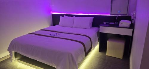 a bedroom with a bed with a purple light on it at Mina Motel 2 in Thuan An