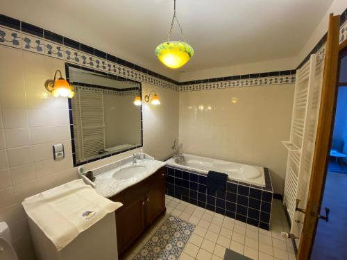 une salle de bain avec une baignoire, un lavabo et un miroir dans l'établissement Gîte spacieux avec piscine et terrasse en village - FR-1-589-637, à Hennecourt