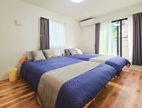 2 große Betten in einem Schlafzimmer mit Holzböden in der Unterkunft 鎌倉江の島 腰越駅徒歩3分海まで5分 2025年新築貸切一戸建て in Kamakura