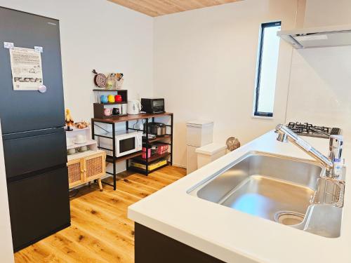 eine Küche mit einer Spüle und einem schwarzen Kühlschrank in der Unterkunft 鎌倉江の島 腰越駅徒歩3分海まで5分 2025年新築貸切一戸建て in Kamakura