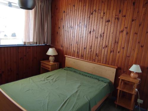 - une chambre avec un lit vert et des murs en bois dans l'établissement Appartement 2 pièces vue montagne, proche pistes et lac - FR-1-814-64, à Besse-et-Saint-Anastaise
