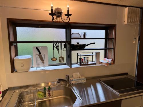 fregadero de cocina con ventana sobre una encimera de cocina en 鶴岡市中心地ゲストハウス, en Tsuruoka