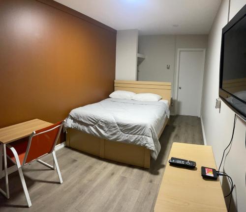 a small room with a bed and a flat screen tv at Inn On Pim in Sault Ste. Marie