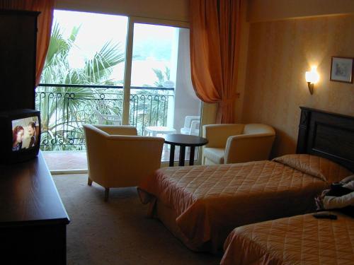 マルマリスにあるCandan Beach Hotelのベッド2台とバルコニーが備わるホテルルームです。