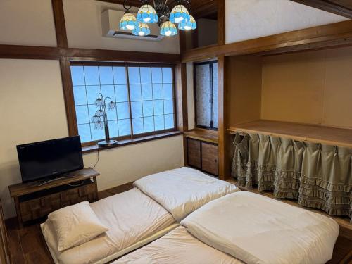 Dos camas en una habitación con TV y ventanas. en 鶴岡市中心地ゲストハウス, en Tsuruoka