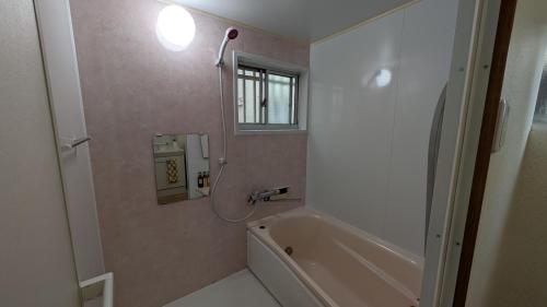 Un baño con bañera y ventana. en Ippaku 一泊, en Izumisano