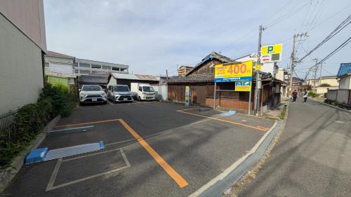 ein Parkplatz mit Autos neben einem Gebäude in der Unterkunft Ippaku 一泊 in Izumi-Sano