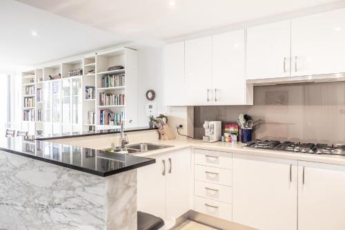a kitchen with white cabinets and a marble counter top at Gorgeous 2-Bed Unit near Riverside Parks in Sydney