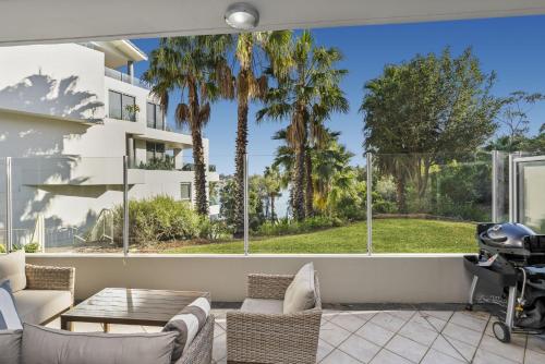 a patio with a table and chairs and palm trees at Gorgeous 2-Bed Unit near Riverside Parks in Sydney