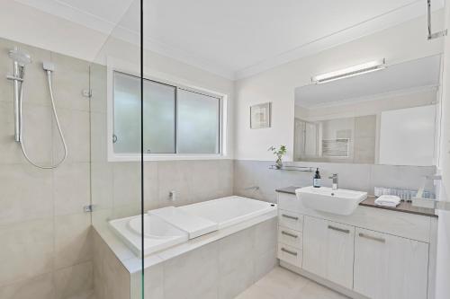 ein weißes Badezimmer mit Badewanne und Waschbecken in der Unterkunft The Wren's Nest in Sandstone Point