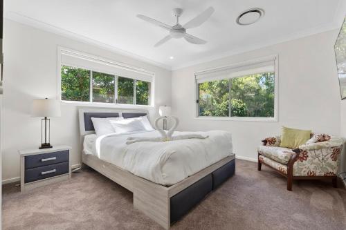 ein Schlafzimmer mit einem Bett, einem Stuhl und zwei Fenstern in der Unterkunft The Wren's Nest in Sandstone Point